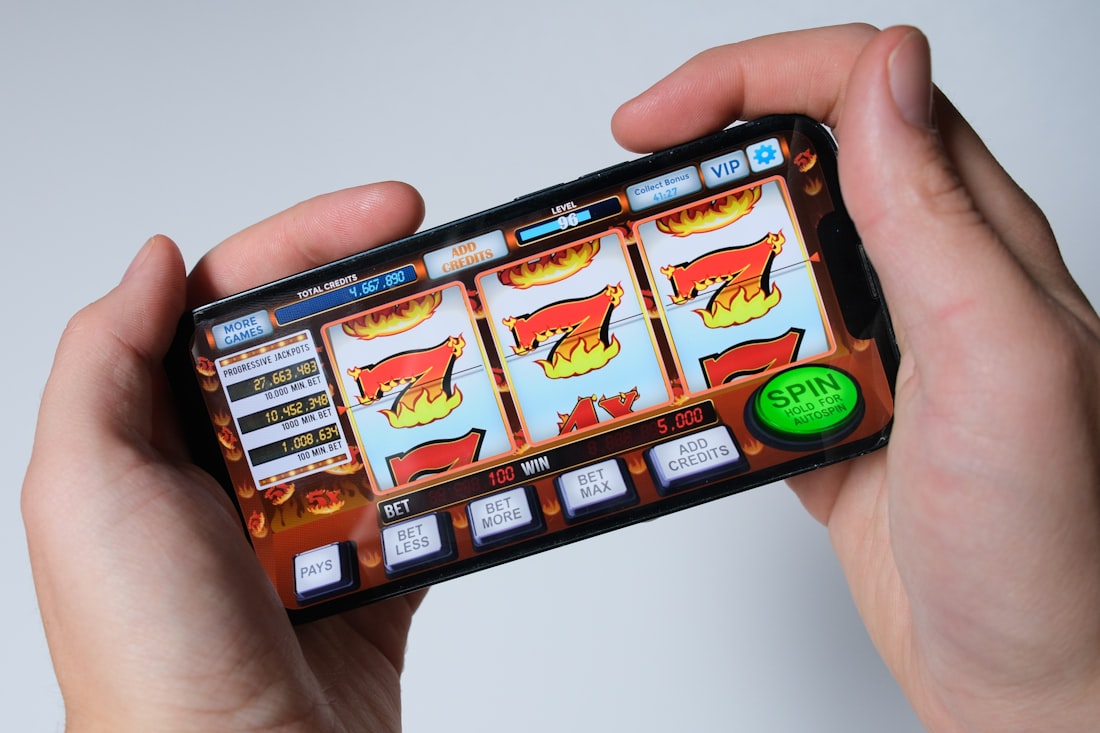 Tangan pengguna memainkan game slot di layar ponsel